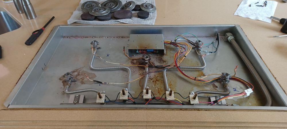 Gas cooktop burner assembly laid out during a service call
